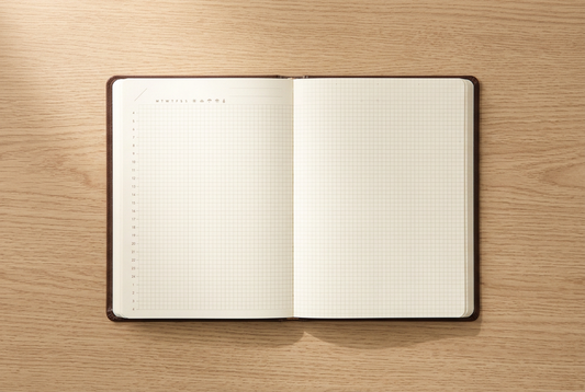 Brown Hibino A6 Free Diary open to its undated two-page spread on a pale oak desk.