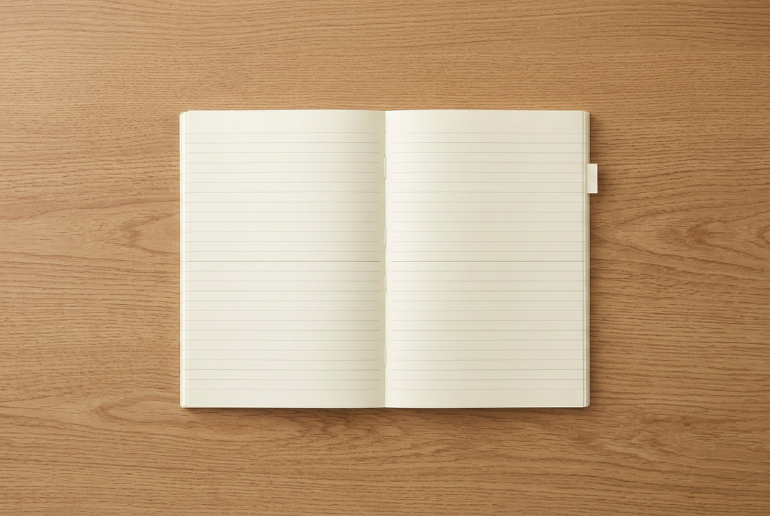 Open cream-colored MD Notebook A5 with lined pages and a small page tab on a warm oak desk.
