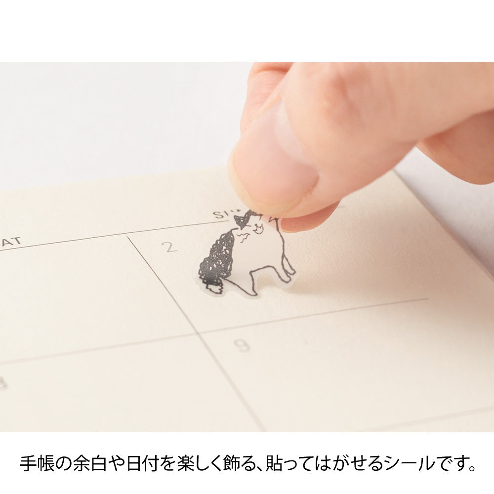 Small cat-shaped stamp being pressed onto a piece of paper with a calendar.