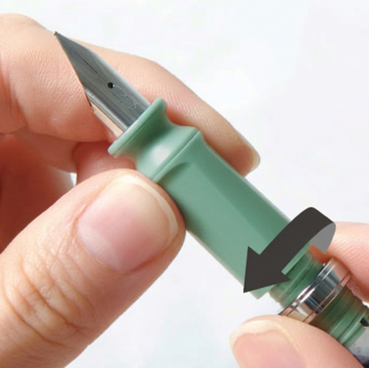 Hand holding a green pen with a close-up of the nib against a white background