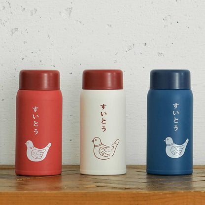 Three thermos bottles in red, white, and blue with bird illustrations on a wooden surface.