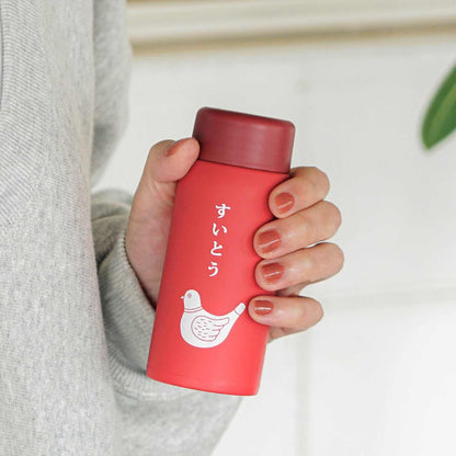 Hand holding a red thermos with a white design on a neutral background